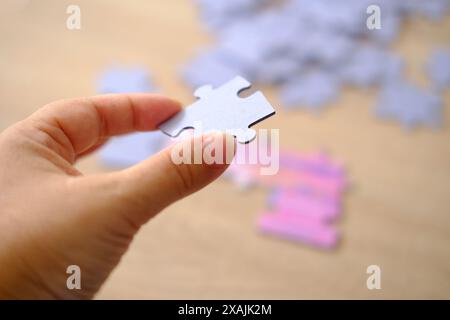 la main féminine tient la pièce de puzzle en carton, les compétences logiques, la résolution de puzzle et l'amélioration de la mémoire, concept d'affaires pour compléter Banque D'Images