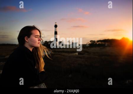 Profil d'un adolescent regardant le coucher du soleil au phare de Bodie Island Banque D'Images
