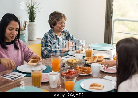 Trois générations prenant le petit déjeuner ensemble dans la salle à manger Banque D'Images