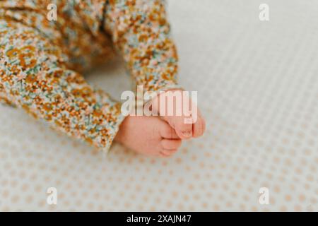 Nouveau-né bébé fille est couché dans le berceau avec les orteils dans l'air Banque D'Images