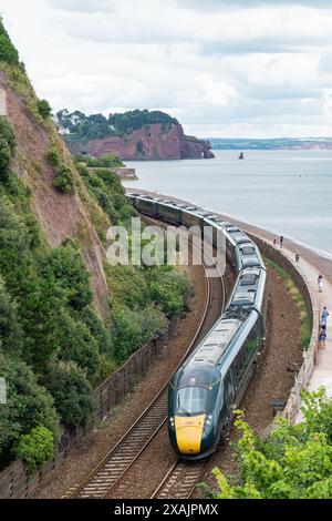 Devon, Angleterre – 21 juillet 2023 : un train de voyageurs du Great Western Railway au départ de Londres Paddington sur la route côtière atmosphérique près de Teignmouth Banque D'Images