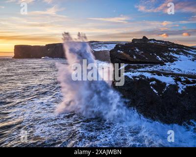 Au crépuscule hivernal, les falaises le long de la côte de la péninsule de Dyrholaey sont incessamment rodées Banque D'Images