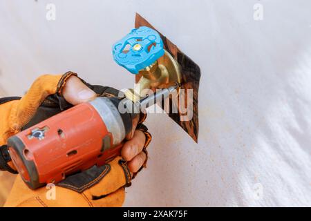 Installation de robinets d'eau extérieurs sur la façade de la résidence par plombier Banque D'Images