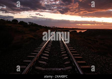 Coucher de soleil sur les voies ferrées passant le long de la côte sud du lac Hart, un lac salé situé à côté de Stuart Highway en Australie méridionale Banque D'Images