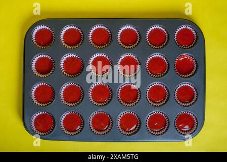 Plateau avec mélange d'ingrédients de cupcake en velours rouge prêt à cuire. Fond jaune. Banque D'Images