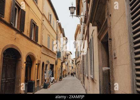 Une scène de rue traditionnelle dans une ville de Toscane, Italie par une journée ensoleillée avec un ciel blanc lumineux et des bâtiments avec des volets et des murs en bois classiques. Banque D'Images