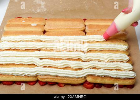 Recouvrir les biscuits savoiardi de crème fouettée. Cuisine domestique. Banque D'Images