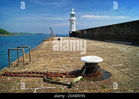 Royaume-Uni, Cornouailles, mur du port extérieur de Mevagissey et phare. Banque D'Images