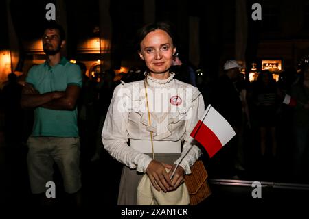 Cracovie, Pologne, 6 juin 2024. Une femme tient un drapeau polonais pendant la campagne électorale de Grzegorz Braun, membre du Parlement polonais (Sejm) au Parlement européen sur la place principale de la vieille ville de Cracovie. Grzegorz Braun est l'un des politiciens polonais les plus radicaux et représente un parti politique d'extrême droite - Konfederacja, qui gagne du soutien en Pologne. Crédit : Dominika Zarzycka/Alamy Live News. Banque D'Images