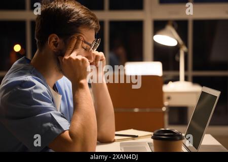 Infirmier fatigué travaillant le soir à table en clinique Banque D'Images