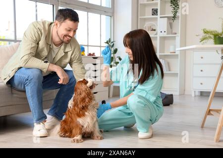 Vétérinaire asiatique femelle avec propriétaire donnant collation au chien mignon en clinique Banque D'Images