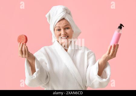 Femme mature avec des produits capillaires après la douche sur fond rose Banque D'Images