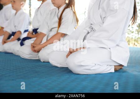 Enfants dans un kimono assis sur le tatami, en gros plan. Pratique de karaté Banque D'Images