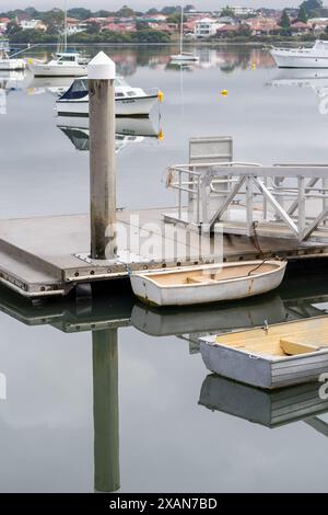 Bateau de rangée sur le lac calme calme avec la réflexion du bateau sur l'eau Banque D'Images