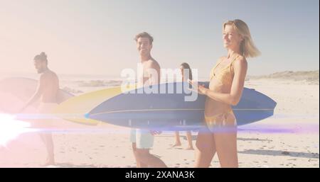 Image de lumière sur des amis heureux et divers marchant sur la plage avec des planches de surf Banque D'Images