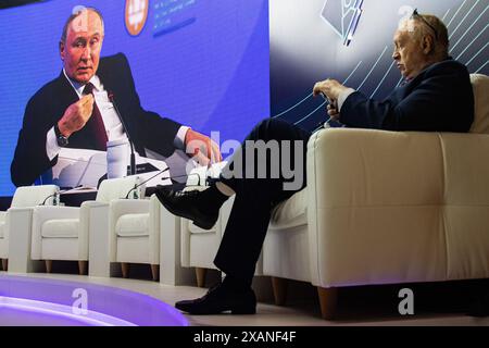 Un homme est assis à l'écran avec une retransmission en direct depuis la salle des congrès du bâtiment Expoforum Exhibition and Convention Center où se tient une réunion plénière avec le président russe Vladimir Poutine dans le cadre de la troisième journée du 27e Forum économique international de Petersburg (SPIEF 2024). Le président russe Vladimir Poutine a tenu une réunion plénière dans le cadre du Forum économique international de Petersburg (SPIEF 2024), où il a discuté des questions clés du développement économique, de l’investissement et de la coopération internationale, sans oublier un certain nombre de questions géopolitiques Banque D'Images