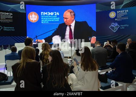 Les visiteurs du forum dans l'une des salles regardent un écran avec une diffusion en direct depuis la salle des congrès du bâtiment Expoforum Exhibition and Convention Center, où une réunion plénière avec le président russe Vladimir Poutine a lieu dans le cadre de la troisième journée du 27e Forum économique international de Petersburg. Le président russe Vladimir Poutine a tenu une réunion plénière dans le cadre du Forum économique international de Petersburg (SPIEF 2024), où il a discuté des questions clés du développement économique, de l'investissement et de la coopération internationale, sans oublier un certain nombre de questions Banque D'Images