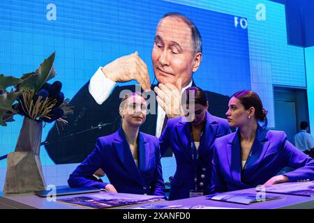 Les filles travaillant au forum se tiennent sur fond de stand avec un écran avec une retransmission en direct de la salle des congrès du bâtiment Expoforum Exhibition and Convention Center où une réunion plénière avec le président russe Vladimir Poutine a lieu dans le cadre de la troisième journée de le 27e Forum économique international de Petersburg. Le président russe Vladimir Poutine a tenu une réunion plénière dans le cadre du Forum économique international de Pétersbourg (SPIEF 2024), où il a discuté des questions clés du développement économique, de l'investissement et de la coopération internationale, mais pas non plus Banque D'Images