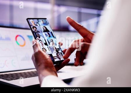 Femme afro-américaine souriante tout en analysant les données sur ordinateur portable dans le webinaire intelligent, discutant des graphiques KPI par vidéoconférence. Banque D'Images