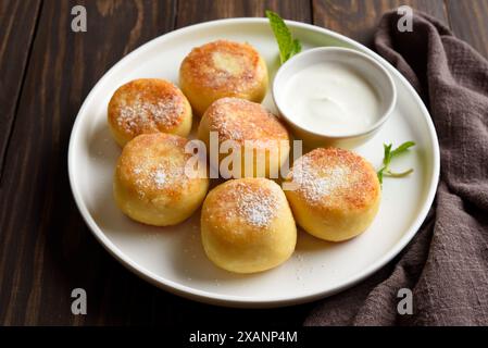 Vue rapprochée des cheesecakes du fromage cottage (beignets syrniki ou caillé) sur fond de bois. Concept d'alimentation saine. Banque D'Images