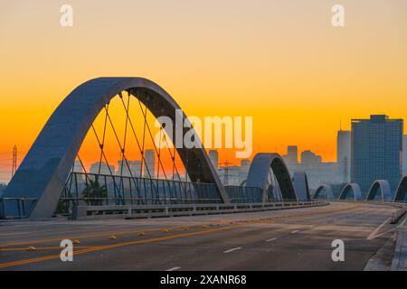 Vue sereine sur le pont de la 6e rue à Los Angeles pendant le coucher du soleil avec le motif d'arc distinctif du pont et les silhouettes urbaines captivantes ag Banque D'Images