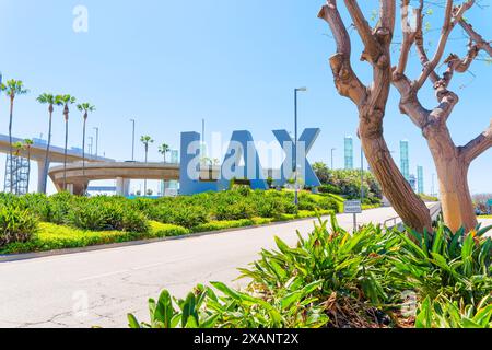 Los Angeles, Californie - 8 avril 2024 : lettres LAX positionnées sur une pelouse bien entretenue avec des arbustes verts et des arbres. Banque D'Images
