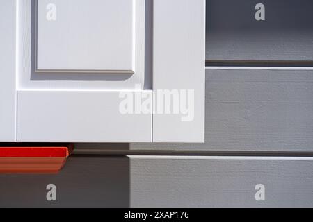 Volets blancs sur une façade grise avec rouge Banque D'Images