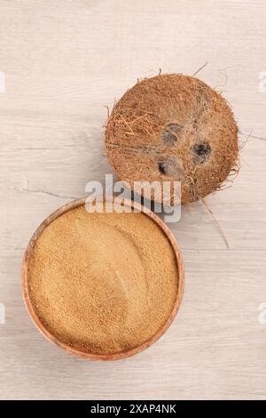 Sucre de noix de coco dans un bol et fruits sur une table en bois clair, vue de dessus Banque D'Images