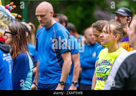 Leeds, Royaume-Uni. 8 juin 2024. Cross Flatts parkrun. Les coureurs de parc de Leeds et d’autres villes se rassemblent pour une course spéciale dans le parc pour commémorer Rob Burrow après son décès la semaine dernière de MND. Les coureurs ont été invités à venir aux couleurs de MND/Leeds Rhino. Les coureurs font une pause pour se souvenir de Rob. Crédit Paul Whitehurst/PBW Media/Alamy Live News Banque D'Images