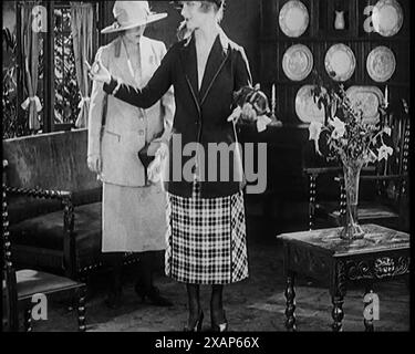 Deux femmes civiles modelant deux pièces costumes et chapeaux posant dans une salle de dessin, années 1920 De "Time to Remember - Teenage Flapper", années 1920 (Reel 1) ; un dcumentaire sur la vie des femmes dans les années 1920 - grand commentaire de Joyce Grenfell. Banque D'Images