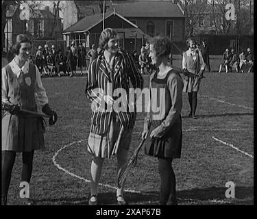 Une femme civile lançant une pièce devant deux jeunes joueuses féminines de crosse avant le début du match, dans les années 1920 De "Time to Remember - Teenage Flapper", années 1920 (Reel 1) ; un dcumentaire sur la vie des femmes dans les années 1920 - grand commentaire de Joyce Grenfell. Banque D'Images