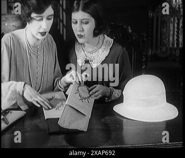 Deux femmes civiles coupant des feuilles de papier pour décorer un chapeau, années 1920 De "Time to Remember - Teenage Flapper", années 1920 (Reel 1) ; un dcumentaire sur la vie des femmes dans les années 1920 - grand commentaire de Joyce Grenfell. Banque D'Images