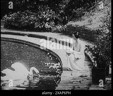La ballerine russe Anna Pavlovna Pavlova nourrissant les cygnes par un étang, années 1920 De "Time to Remember - Teenage Flapper", années 1920 (Reel 4) ; un dcumentaire sur la vie des femmes dans les années 1920 - grand commentaire de Joyce Grenfell. Banque D'Images