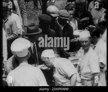 Civils américains servant des repas pour une grande foule sur une file d'attente en plein air, années 1930 '...l'armée Bonus [les vétérans américains qui demandent le soutien du gouvernement pendant la dépression] campent sur le pas de Washington, exigeant un traitement décent... un salaire décent au lieu d'une existence'. De "Time to Remember - The Tough Guys", années 1930 (Reel 1) ; un film documentaire principalement sur la vie dans la dépression et les gangsters américains. Banque D'Images