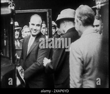 Alphonse Gabriel Capone alias 'Al Capone' entrant dans une voiture surveillée par une petite foule, 1930s. "Ce fut la plus grande surprise du siècle quand Gentle Al a été mis de côté pendant onze ans pour ne pas avoir payé son impôt sur le revenu". De "Time to Remember - The Tough Guys", années 1930 (Reel 1) ; un film documentaire, principalement sur la vie dans la dépression et les gangsters américains. Banque D'Images