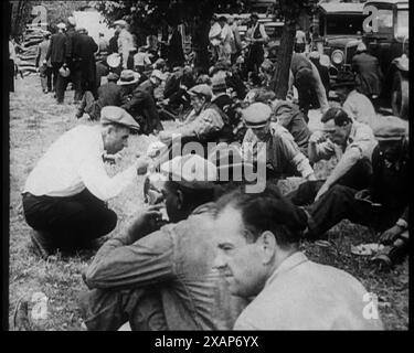 Grande foule de civils américains mangeant des repas à l'extérieur, années 1930 '...l'armée Bonus [les vétérans américains qui demandent le soutien du gouvernement pendant la dépression] campent sur le pas de Washington, exigeant un traitement décent... un salaire décent au lieu d'une existence'. De "Time to Remember - The Tough Guys", années 1930 (Reel 1) ; un film documentaire principalement sur la vie dans la dépression et les gangsters américains. Banque D'Images