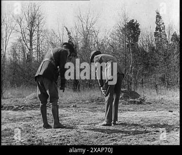 Des officiers de police américains enquêtant sur les empreintes de pas devant la maison de l'aviateur américain Charles Augustus Lindbergh lors de l'enquête sur l'enlèvement, dans les années 1930 L'affaire d'enlèvement de bébé Lindbergh de 1932 - "le crime du siècle". « La police, submergée par le crime et l'attention qu'elle attire... fait de son mieux... l'une des plus grandes et des plus vastes recherches de l'histoire peigne la zone autour de la maison Lindbergh [dans le New Jersey] ». De "Time to Remember - The Tough Guys", années 1930 (Reel 2) ; film documentaire, principalement sur la vie dans la dépression et les gangsters américains. Banque D'Images