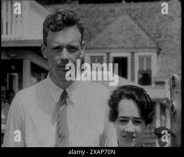 L'aviateur américain Charles Augustus Lindbergh et sa femme Anne Morrow Lindbergh posant pour la caméra devant leur maison, dans les années 1930 L'affaire d'enlèvement de bébé Lindbergh de 1932 - "le crime du siècle". Charles Auguste, le jeune fils du Lindbergh, fut enlevé et assassiné plus tard. De "Time to Remember - The Tough Guys", années 1930 (Reel 2) ; film documentaire, principalement sur la vie dans la dépression et les gangsters américains. Banque D'Images