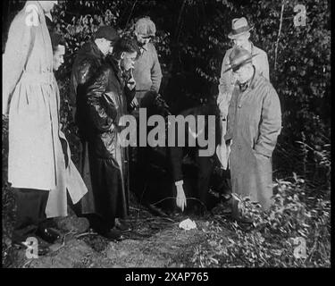 Policiers américains cherchant la zone à l'extérieur de la maison de l'aviateur américain Charles Augustus Lindbergh lors d'une enquête sur un enlèvement, dans les années 1930 L'affaire d'enlèvement de bébé Lindbergh de 1932 - "le crime du siècle". "Dans l'obscurité, à moins de cinq miles de Hopewell [New Jersey], les hommes ont trouvé le corps du bébé Lindbergh". De "Time to Remember - The Tough Guys", années 1930 (Reel 2) ; film documentaire, principalement sur la vie dans la dépression et les gangsters américains. Banque D'Images