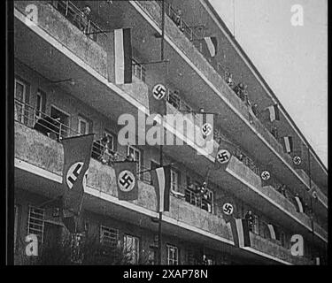 Les gens agitent les drapeaux du parti nazi et les drapeaux allemands de 1867-1918 depuis les balcons, 1933. La montée du nazisme en Allemagne. Bien qu'ils n'aient pas obtenu une majorité écrasante, les nazis ont fait croire qu'ils l'avaient fait. Avec leurs techniques novatrices, leur attrait et leurs méthodes vivantes, il ne faisait guère de doute qu'ils étaient en mesure de commander tout le soutien dont ils avaient besoin ». De "Time to Remember - The Time of the Monster", 1933 (bobine 2) ; film documentaire sur les événements de 1933, la montée de Roosevelt et Hitler. Banque D'Images