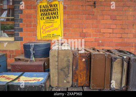 Vieilles valises en cuir et en toile empilées sur les chariots de la gare ferroviaire au quai de la gare ferroviaire de Llangollen, Llangollen, pays de Galles. Banque D'Images