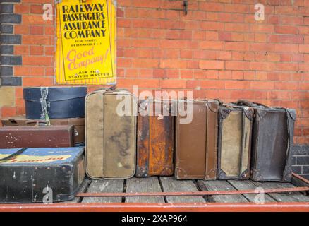 Vieilles valises en cuir et en toile empilées sur les chariots de la gare ferroviaire au quai de la gare ferroviaire de Llangollen, Llangollen, pays de Galles. Banque D'Images