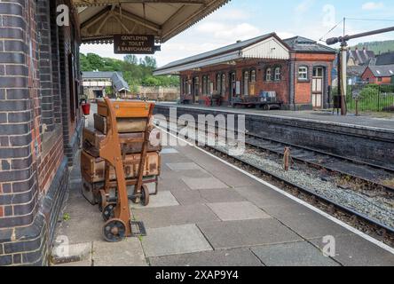 Vieilles valises en cuir et en toile empilées sur les chariots de la gare ferroviaire au quai de la gare ferroviaire de Llangollen, Llangollen, pays de Galles. Banque D'Images