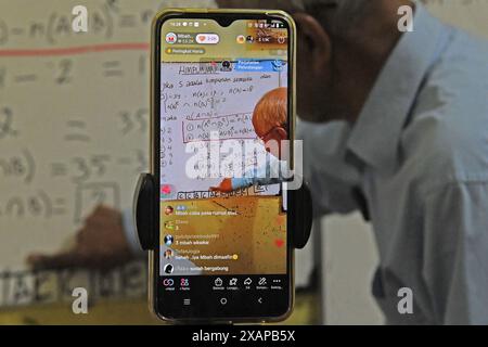 7 juin 2024, Purworejo, Java central, Purworejo : MELAN Achmad (78) un professeur de mathématiques à la retraite enseigne et apprend toujours en utilisant les médias sociaux avec l'aide de son fils comme vidéaste via téléphone portable à son domicile de Purworejo, Java central. MELAN Achmad, communément appelé Mbah Matematika, est à la retraite depuis 2003, mais son enthousiasme pour le partage des connaissances n'a jamais été éteint en utilisant les médias sociaux TikTok appelés ''˜@binaprestasiwa' pour atteindre les étudiants en partageant des matériaux mathématiques pour le primaire, le collège et le lycée, et en discutant des questions de test d'entrée à l'université. MBA Banque D'Images