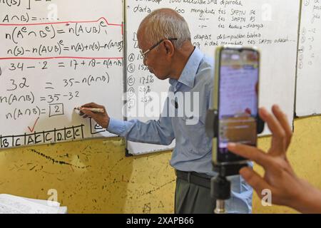 7 juin 2024, Purworejo, Java central, Purworejo : MELAN Achmad (78) un professeur de mathématiques à la retraite enseigne et apprend toujours en utilisant les médias sociaux avec l'aide de son fils comme vidéaste via téléphone portable à son domicile de Purworejo, Java central. MELAN Achmad, communément appelé Mbah Matematika, est à la retraite depuis 2003, mais son enthousiasme pour le partage des connaissances n'a jamais été éteint en utilisant les médias sociaux TikTok appelés ''˜@binaprestasiwa' pour atteindre les étudiants en partageant des matériaux mathématiques pour le primaire, le collège et le lycée, et en discutant des questions de test d'entrée à l'université. MBA Banque D'Images