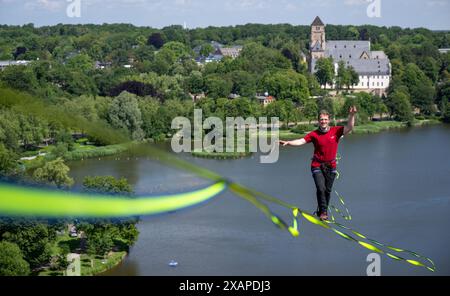 08 juin 2024, Saxe, Chemnitz : Jens Decke se balance à une hauteur de 50 mètres sur une ligne haute au-dessus de l'étang du château à Chemnitz. La slackline de 630 mètres de long est tendue entre la tour de l'église du château (à l'arrière) et un immeuble de grande hauteur et est considérée comme la plus longue ligne dans une zone urbaine en Allemagne. Les slackliners passent un peu moins de 45 minutes sur un tronçon. La ligne s'étend sur les terrains du festival de la démocratie 'Kosmos'. Selon les organisateurs, un total de plus de 200 articles du programme seront offerts en une journée. Environ 50 000 visiteurs sont attendus au festival. Photo Banque D'Images