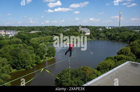 08 juin 2024, Saxe, Chemnitz : Jens Decke se balance à une hauteur de 50 mètres sur une ligne haute au-dessus de l'étang du château à Chemnitz. La slackline de 630 mètres de long est tendue entre la tour de l'église du château (à l'arrière) et un immeuble de grande hauteur et est considérée comme la plus longue ligne dans une zone urbaine en Allemagne. Les slackliners passent un peu moins de 45 minutes sur un tronçon. La ligne s'étend sur les terrains du festival de la démocratie 'Kosmos'. Selon les organisateurs, un total de plus de 200 articles du programme seront offerts en une journée. Environ 50 000 visiteurs sont attendus au festival. Photo Banque D'Images