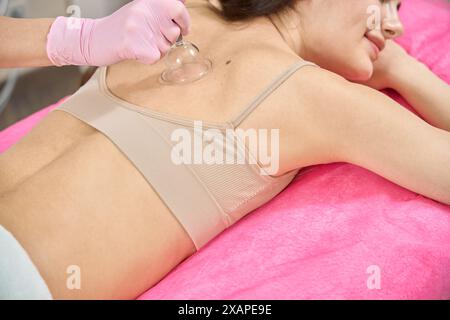 Femme souriante obtenant le massage de ventouse pour les douleurs dans le haut du dos Banque D'Images