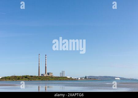 Plage de Sandymount à marée basse avec les cheminées emblématiques de Poolbeg en arrière-plan par une journée ensoleillée. Le ciel est bleu vif contre les cheminées Banque D'Images