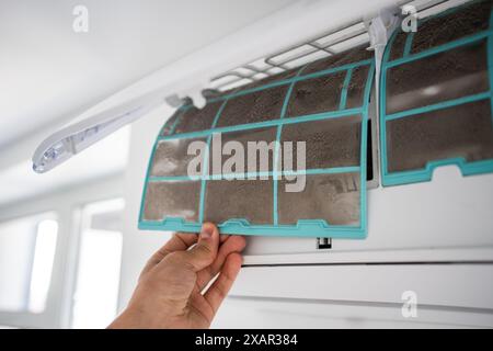 Homme enlevant le filtre grossier sale et poussiéreux du climatiseur pour le lavage, le nettoyage. La poussière est la cause de la maladie Banque D'Images